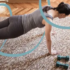 Kobieta ćwiczy pilates w domu, patrząc na ekran laptopa. To świetny sposób, by dowiedzieć się, pilates co to jest i jak zacząć.