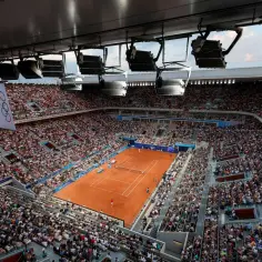 Widok z góry na pełny stadion tenisowy podczas meczu WTA 500. Na korcie ziemnym toczy się zacięta gra, a trybuny wypełnia liczna publiczność.