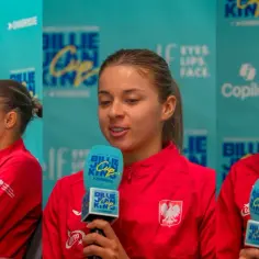 Trzy tenisistki w czerwonych strojach z godłem Polski udzielają wywiadu podczas Billie Jean King Cup.