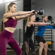 Trzy osoby wykonują ćwiczenia z kettlebellami, co to jest trening obwodowy.