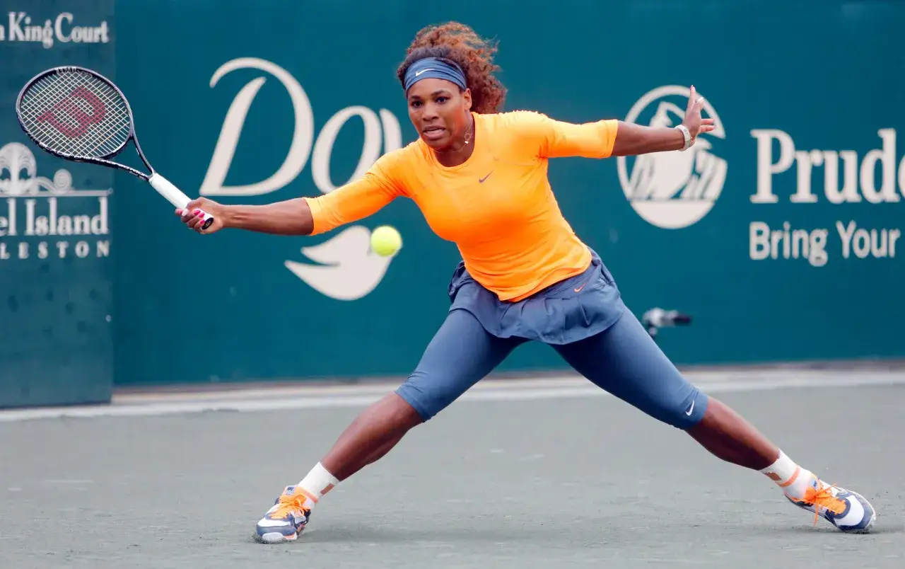 Serena Williams w akcji podczas turnieju ATP, odbija piłkę zza linii końcowej.
