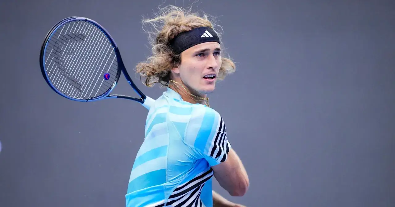 Zverev w akcji, z włosami rozwianymi na wietrze, uderza piłkę rakietą.